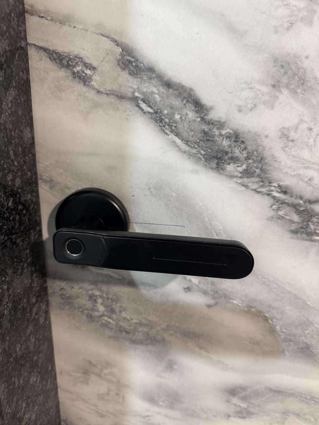 Black door handle on a marble door